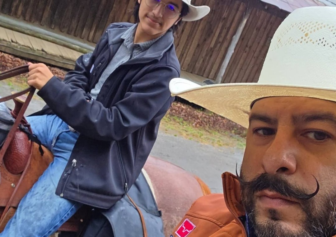 Tex Ruiz out on horseback in his Take the Reins jacket and straw hat